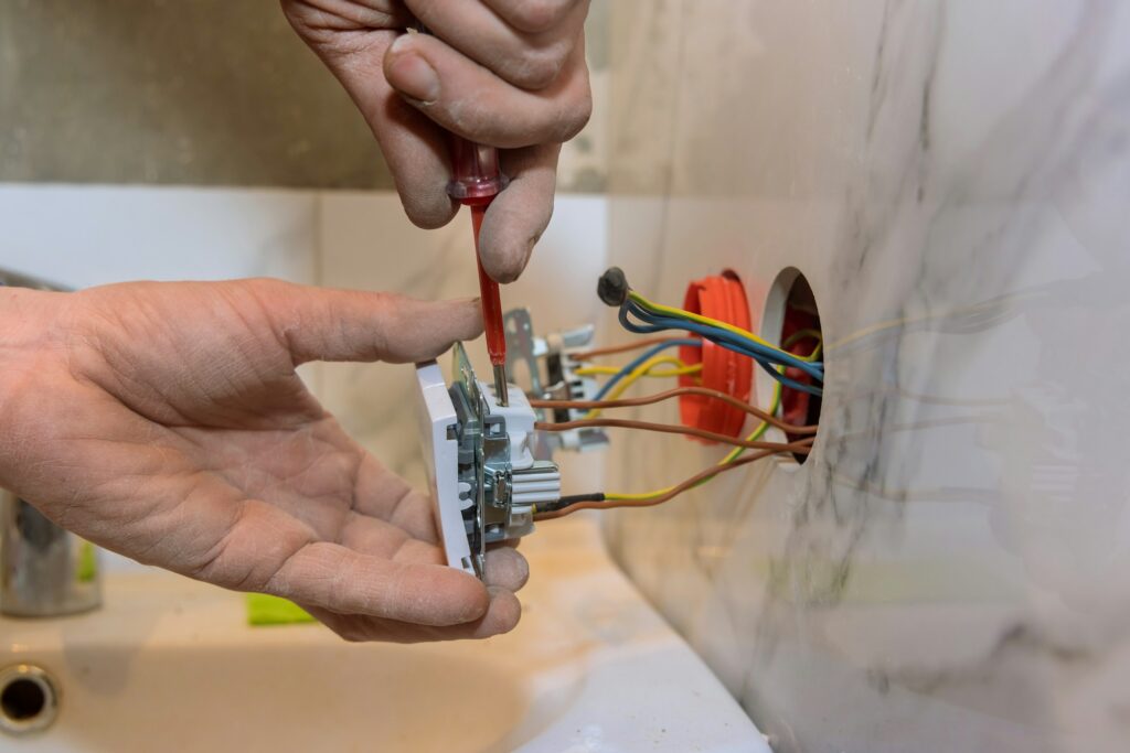 Electrician in mounting electric sockets on the wall